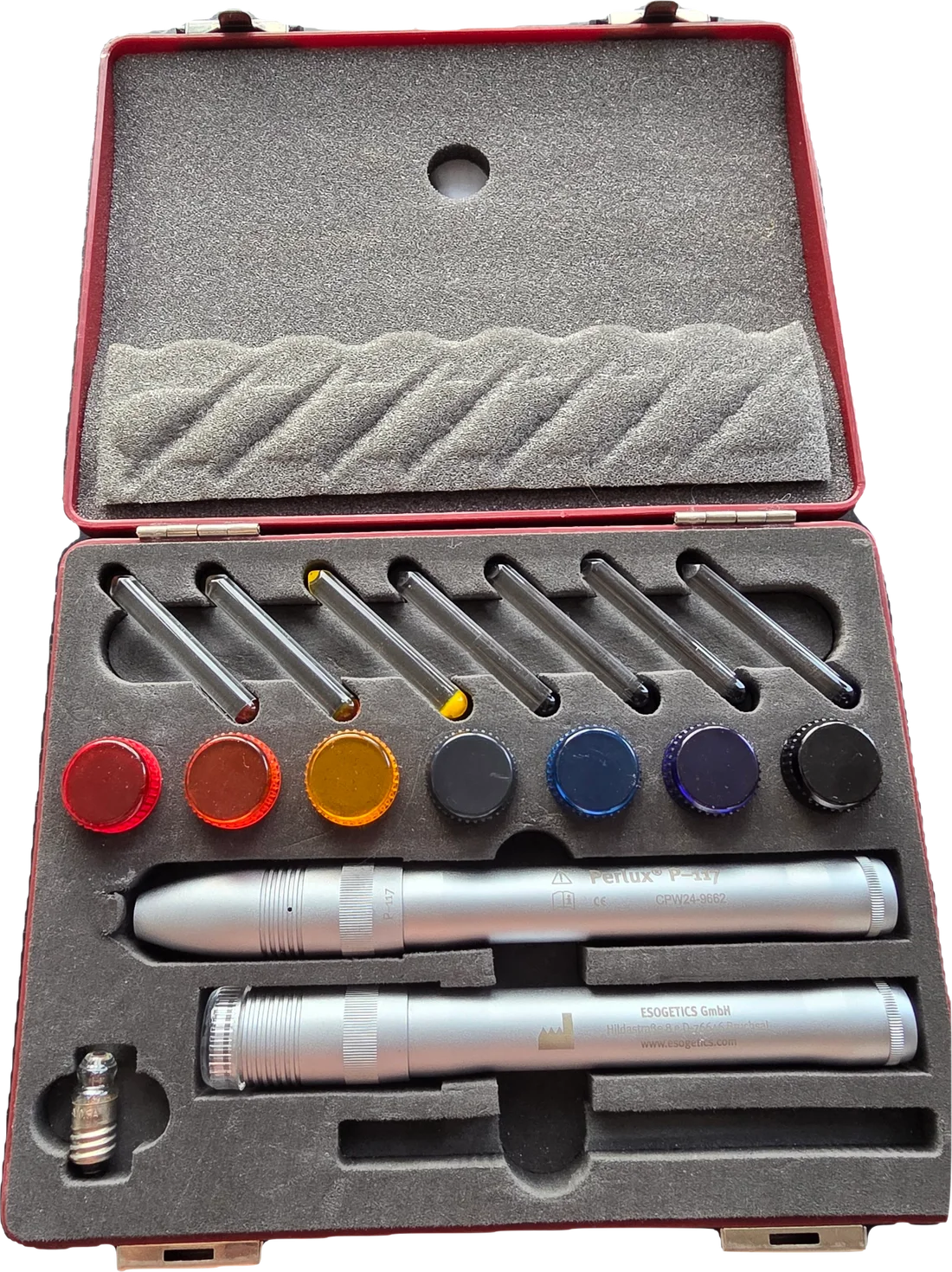 The open case: seven glass colour rods, seven colour filter caps, two silver Perlux pens, a point probe and a spare bulb in grey foam